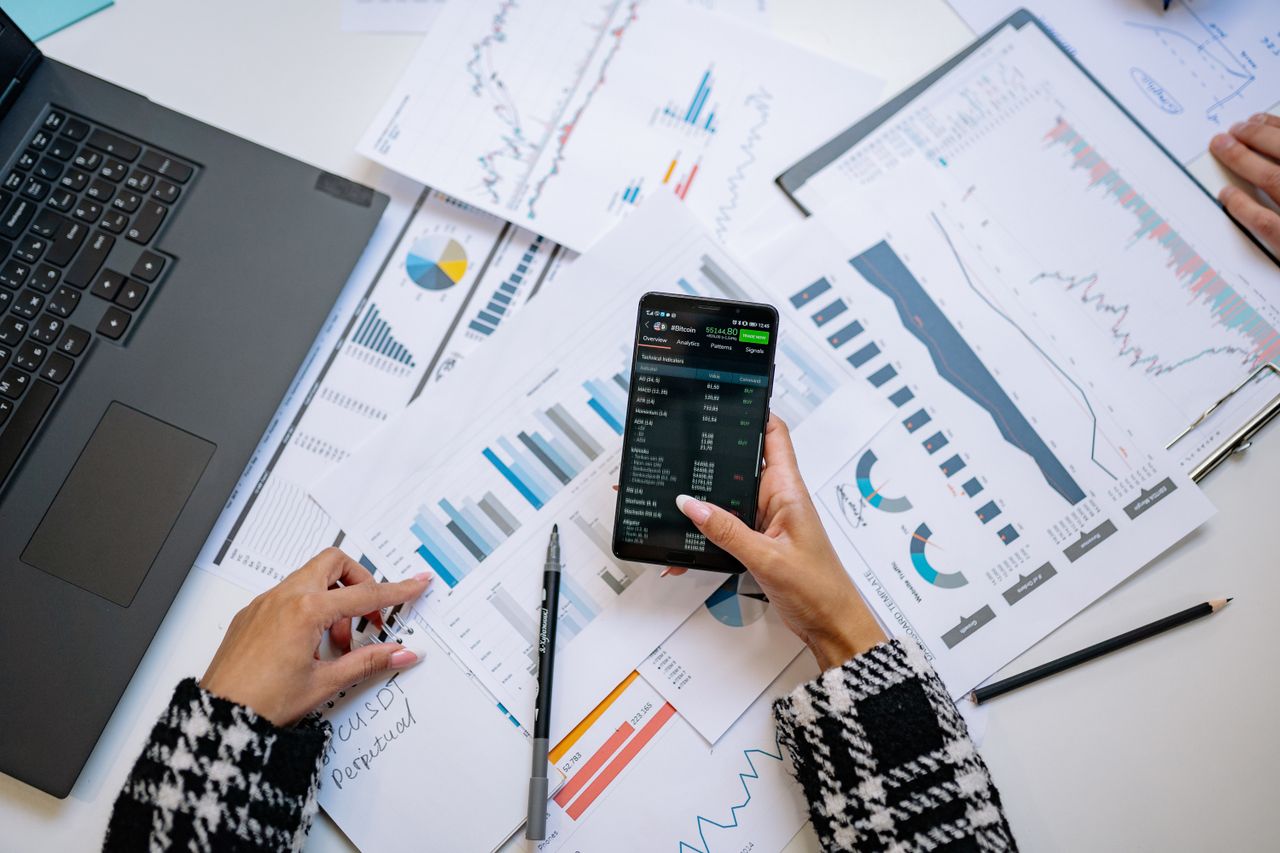 Une vue en plongée sur des graphiques et un smartphone dans un bureau, mettant en avant l’analyse de données.